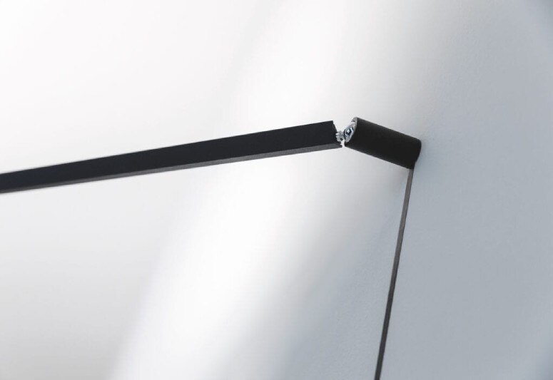 A close-up of Endless conductive tape leading into Meridiana wall light's pivot point, evoking the shadow of the extended arm.