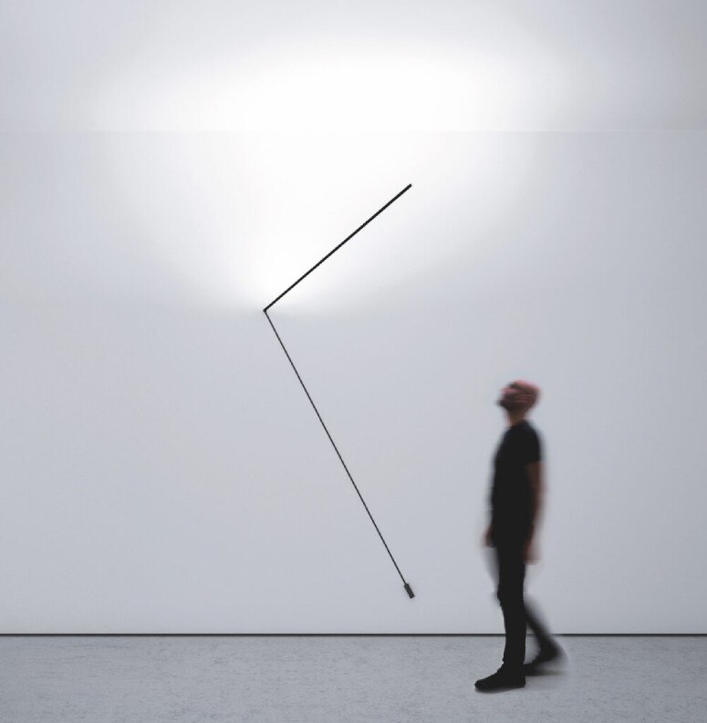 A studio photo featuring Davide Groppi's signature blurred presence gazing up at the arm of Meridiana wall light.